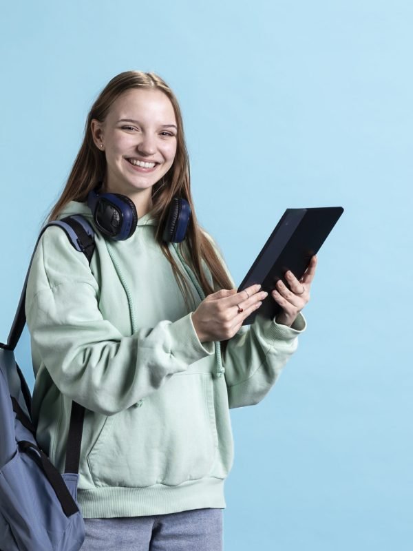 Overjoyed teenager using tablet, laughing at amusing social media posts on feed. Joyous person browsing internet websites, amused by funny memes, isolated over studio backdrop